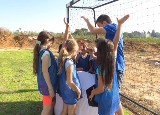 בלונים ושוקולד - קבוצת הבנות מרימות ידיים לפני המשחק ביום הולדת כדורגל