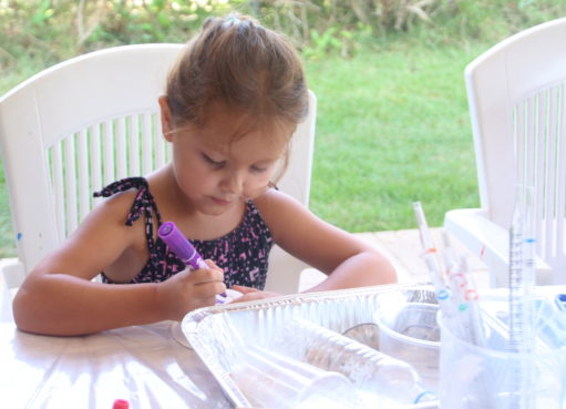 ילדה כותבת את השם על קערה ביום הולדת מדעי