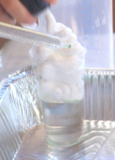 מטפטפים צבע מאכל בפיפטה לכוס בניסוי סערה בכוס ביום הולדת מדעי