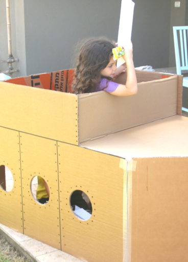 ילדה משחקת עם פריסקופ בתוך צוללת מקרטון ביום הולדת מדעי
